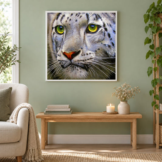 Schneeleopard mit grünen Augen als gerahmtes Diamond Painting im Wohnzimmer